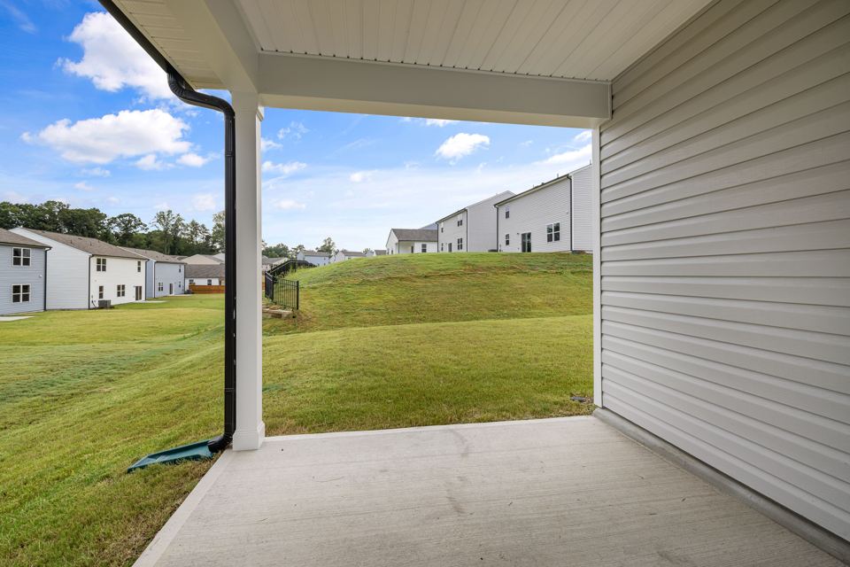 Plain concrete patio beside a lawn and covered seating area